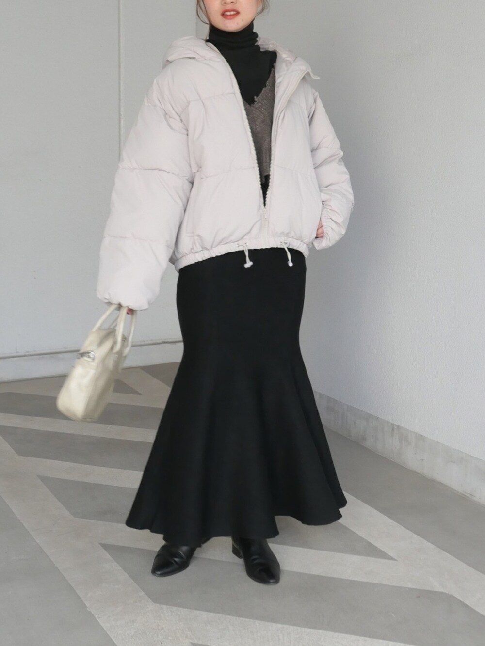 ベージュ系のショルダーバッグ、ホワイト系のダウンジャケット/コート、ブラック系のTシャツ/カットソーを着用したレディースの冬コーディネートの2枚目の写真