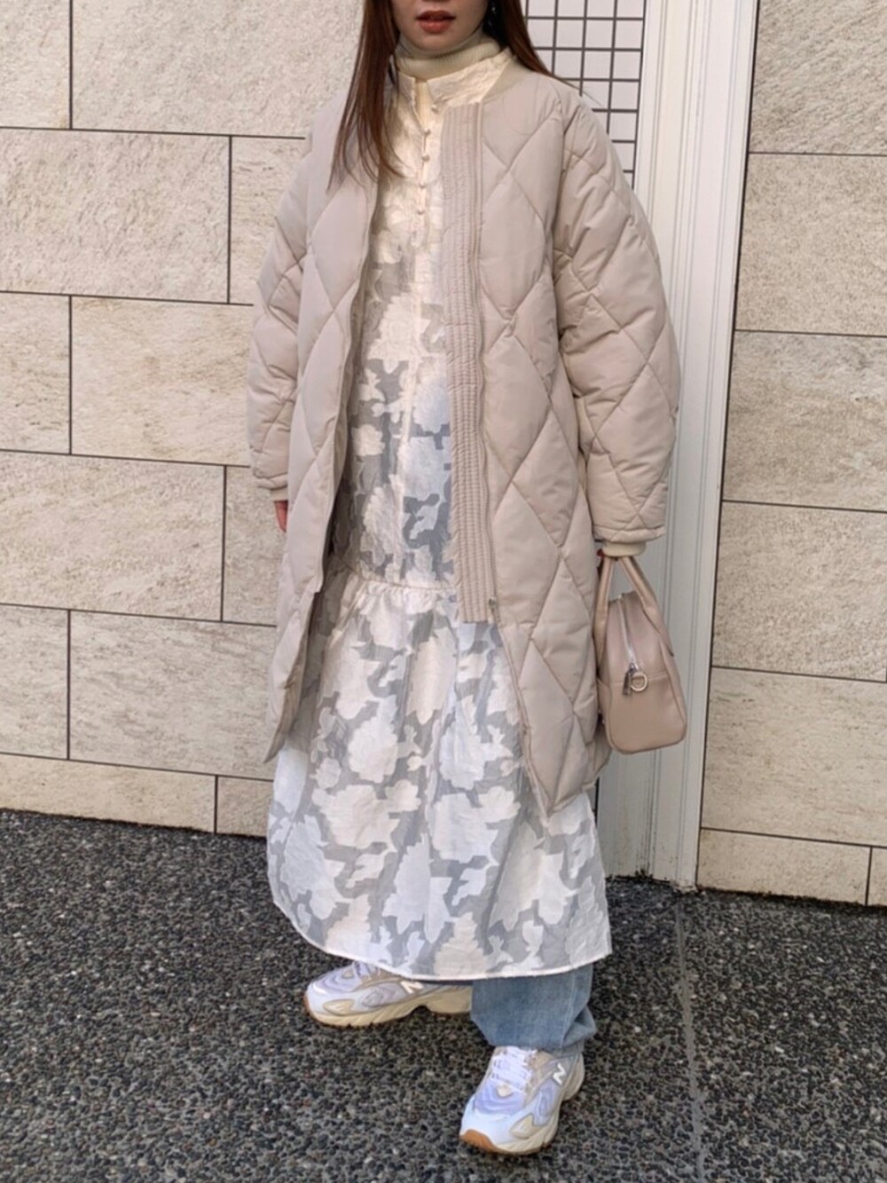 ホワイト系のダウンジャケット/コート、ホワイト系のワンピース、ブルー系のデニムパンツを着用したレディースの冬コーディネートの2枚目の写真