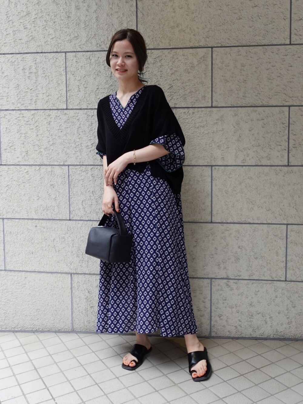 ブラック系のショルダーバッグ、ブルー系のワンピース、ブラック系のベストを着用したレディースの春コーディネートの2枚目の写真