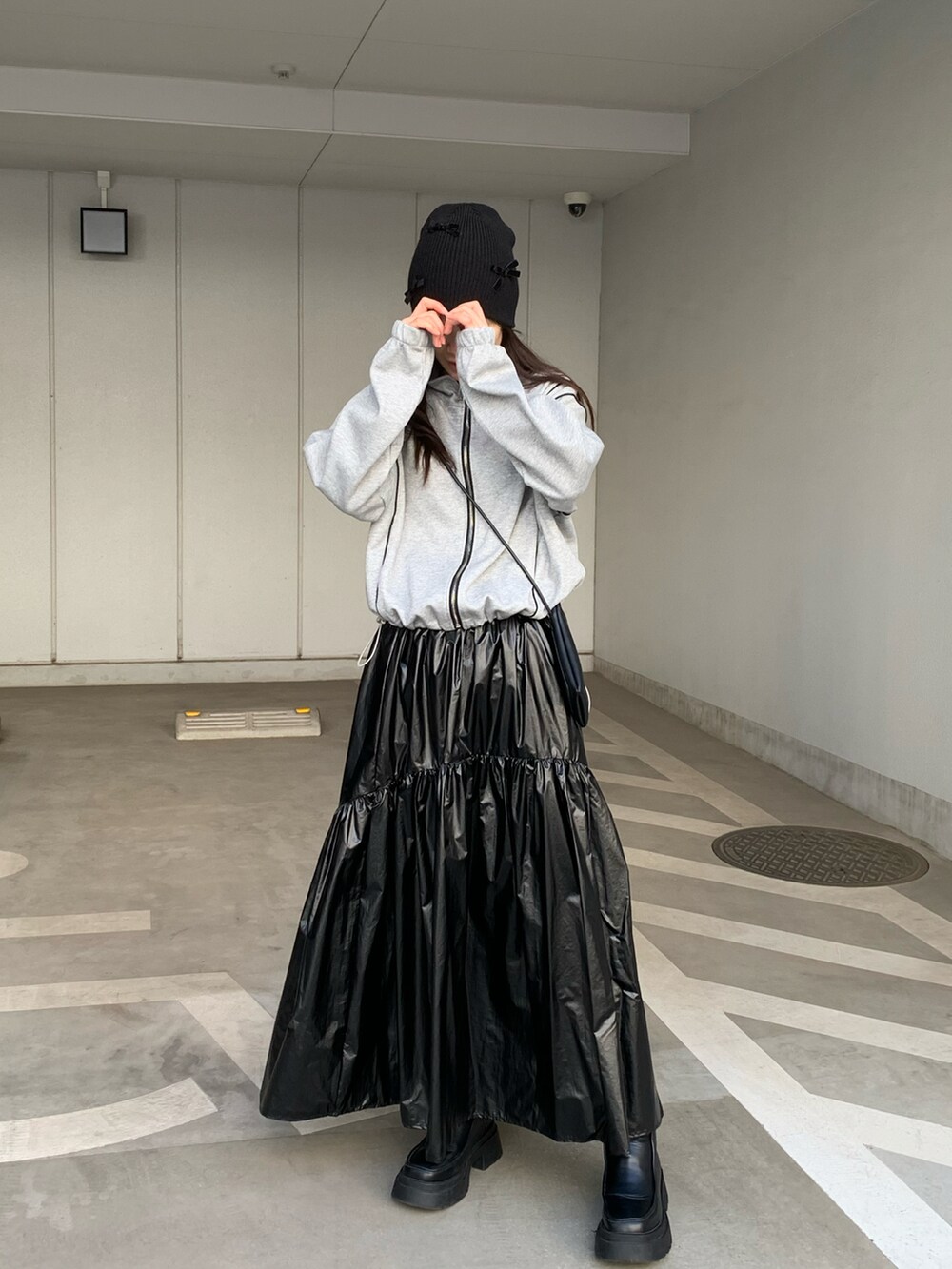 グレー系のジャージ、ブラック系のスカート、ブラック系のショルダーバッグを着用したレディースの冬コーディネートの2枚目の写真