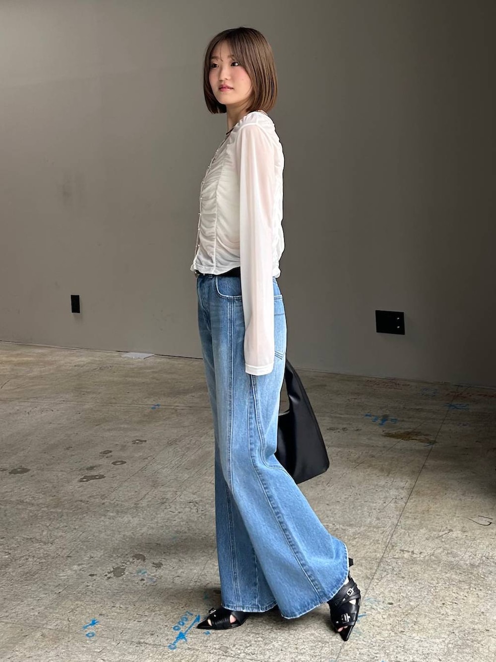 ブルー系のデニムパンツ、ブラック系のトートバッグ、ホワイト系のTシャツ/カットソーを着用したレディースの春コーディネートの4枚目の写真