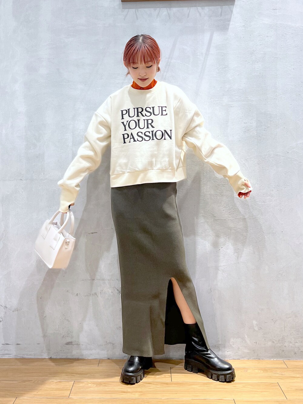 ホワイト系のショルダーバッグ、ベージュ系のスウェット、グリーン系のスカートを着用したレディースの冬コーディネートの2枚目の写真