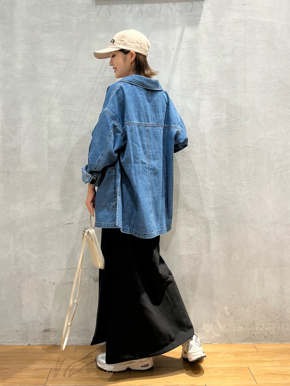 ブルー系のデニムジャケット、ブラック系のキャミソール、ブラック系のスカートを着用したレディースの秋コーディネートの2枚目の写真