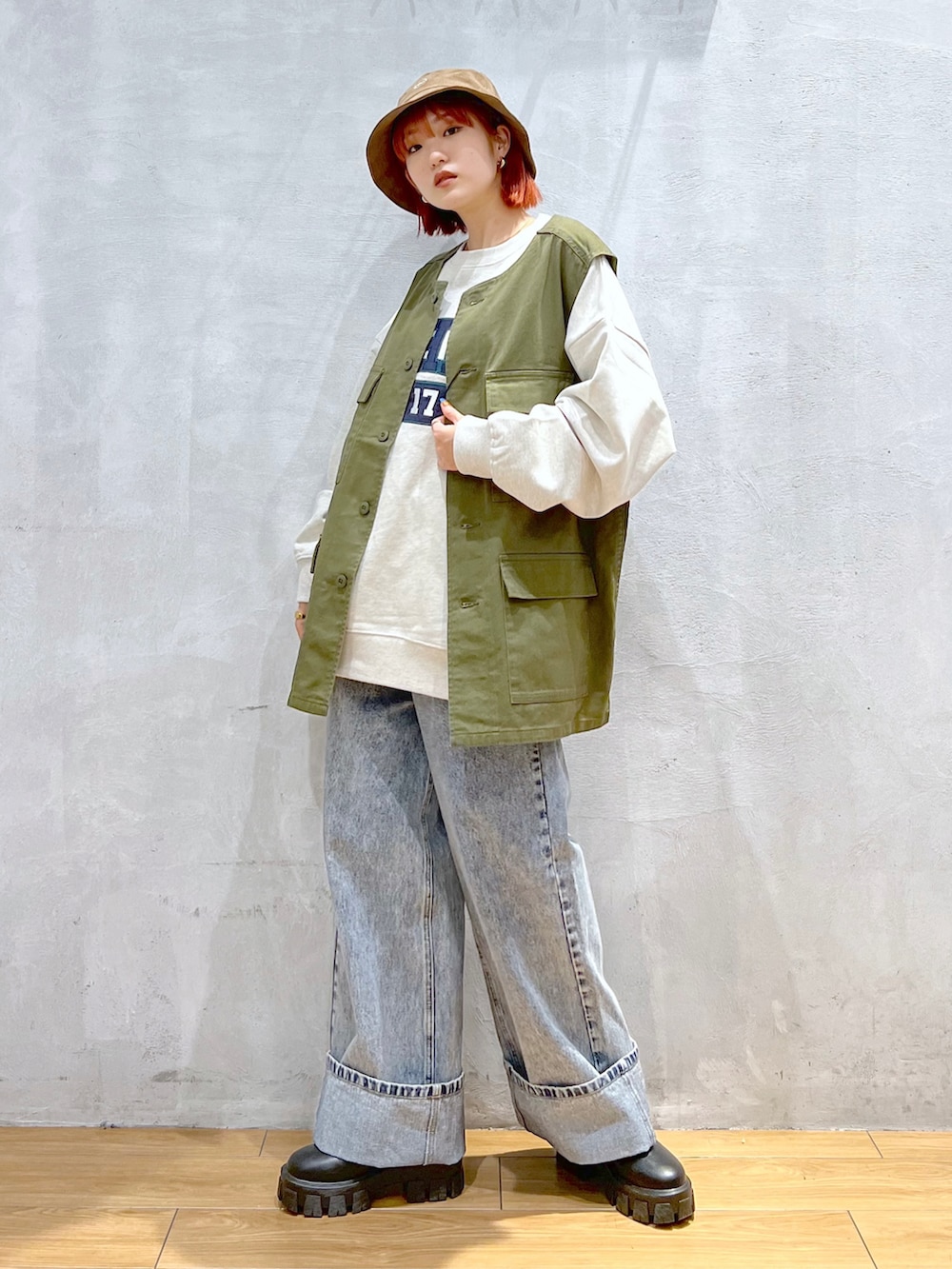 ブルー系のデニムパンツ、グリーン系のベスト、ベージュ系のスウェットを着用したレディースの秋コーディネートの3枚目の写真