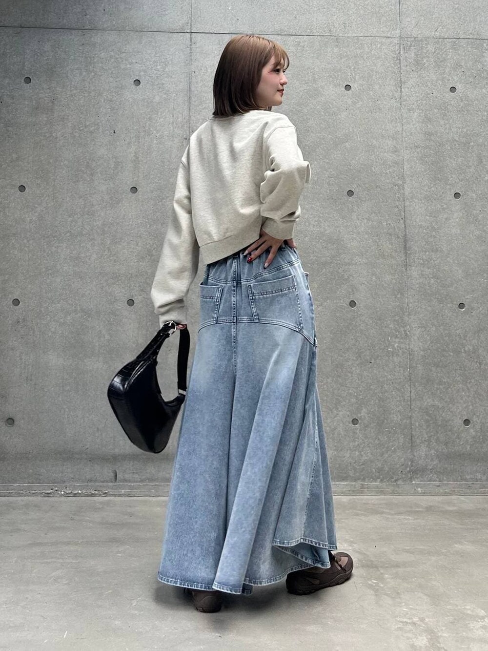 ブラウン系のスニーカー、グレー系のスウェット、ブルー系のデニムスカートを着用したレディースの冬コーディネートの3枚目の写真
