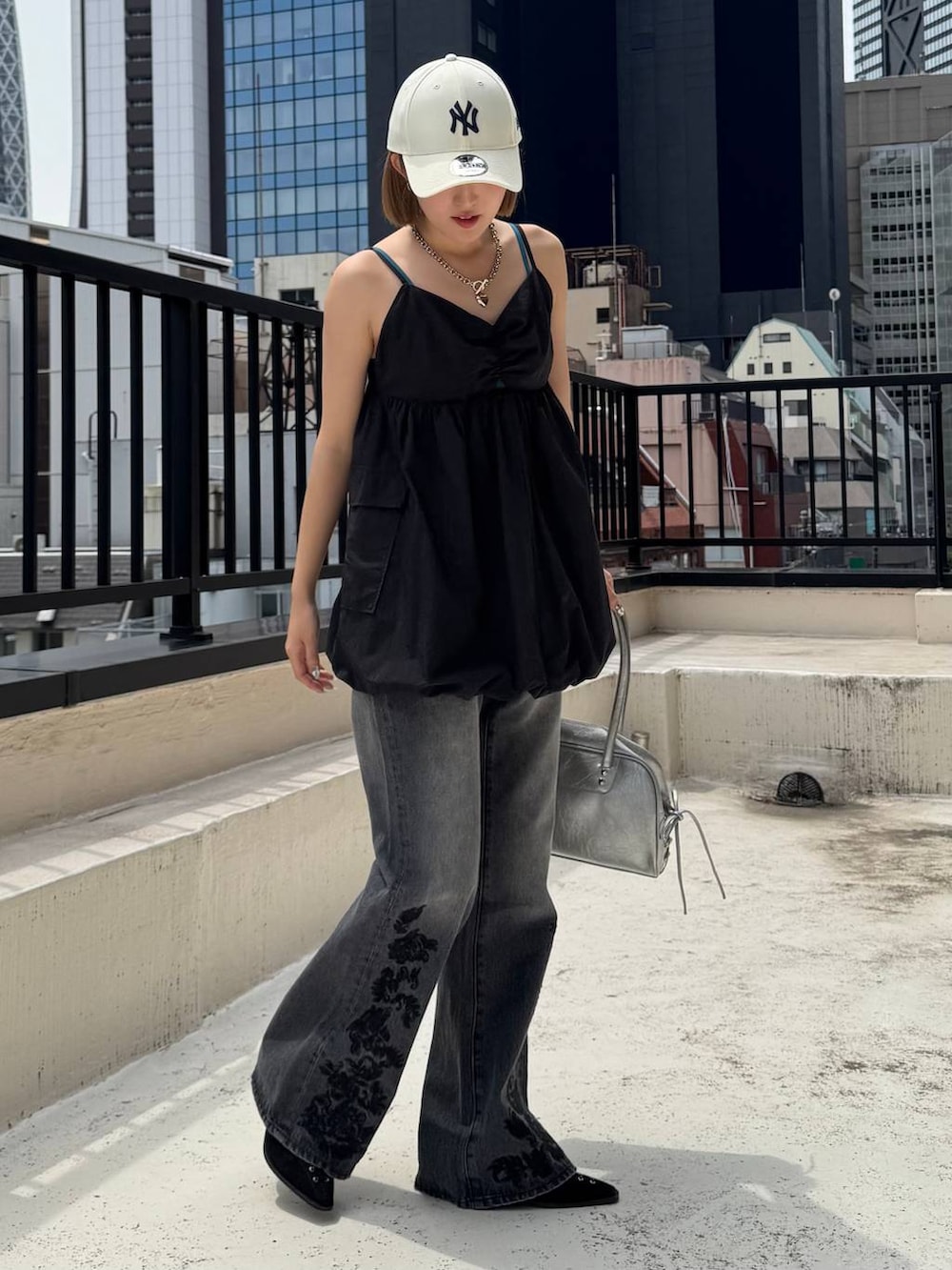 ブラック系のパンプス、ブラック系のデニムパンツ、グリーン系のキャミソールを着用したレディースの夏コーディネートの3枚目の写真