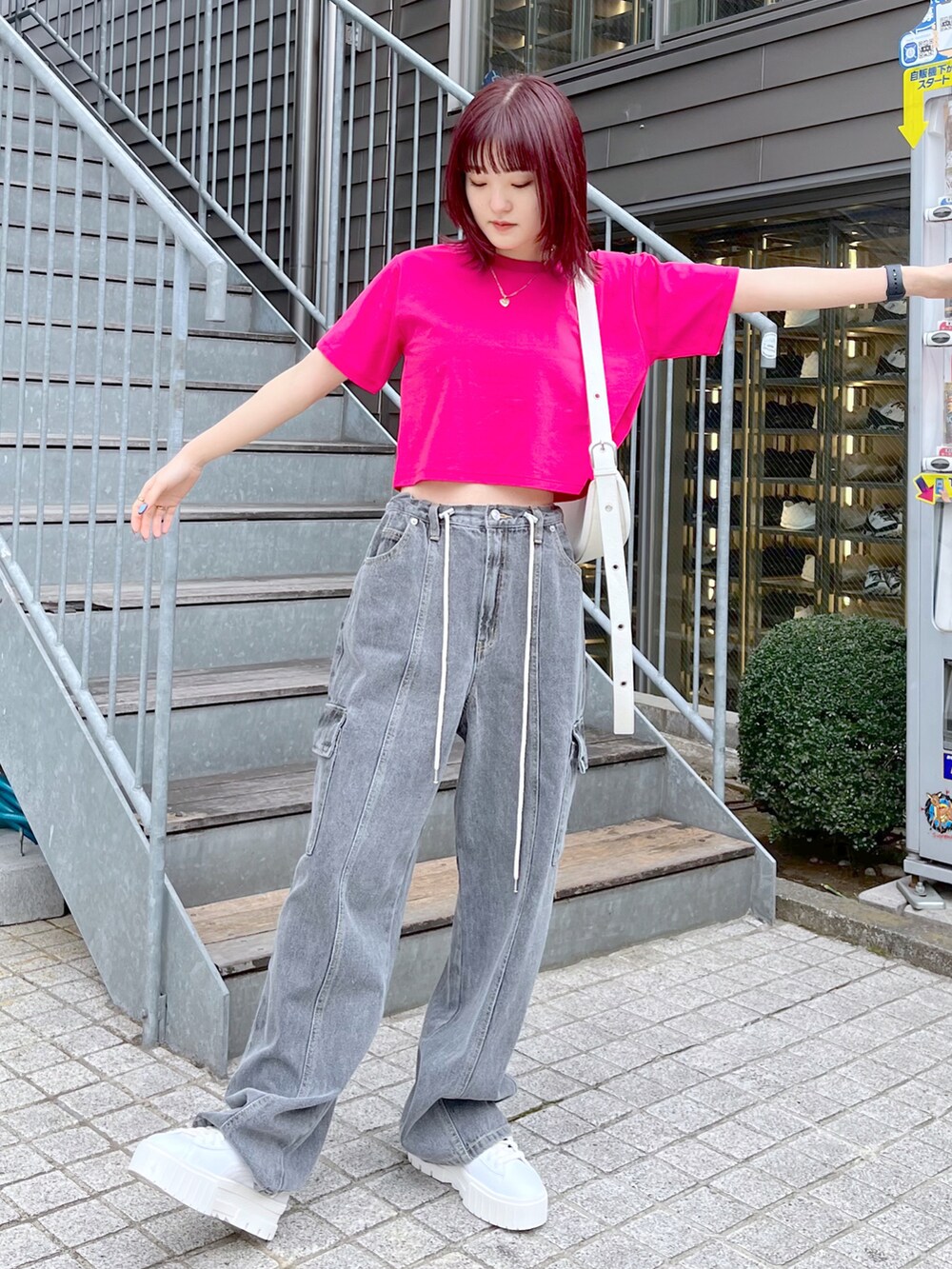 ブラック系のデニムパンツ、ホワイト系のショルダーバッグ、ピンク系のTシャツ/カットソーを着用したレディースの春コーディネートの2枚目の写真