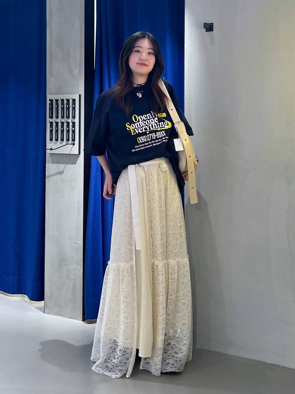 ブラック系のスニーカー、ベージュ系のショルダーバッグ、ブルー系のTシャツ/カットソーを着用したレディースの夏コーディネートの3枚目の写真