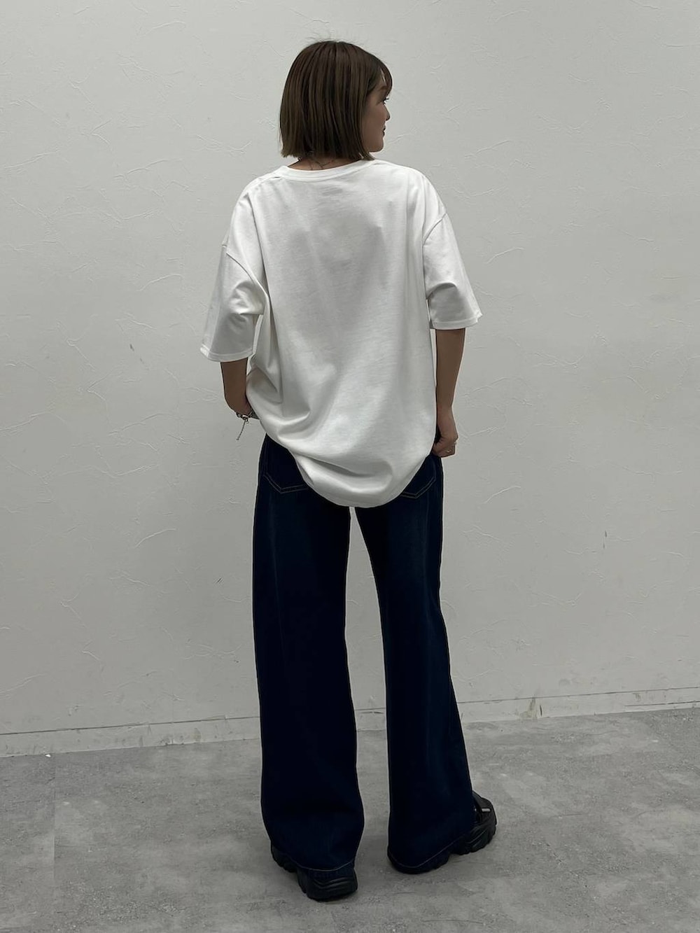 ブルー系のデニムパンツ、ブラック系のサンダル、ホワイト系のTシャツ/カットソーを着用したレディースの夏コーディネートの5枚目の写真