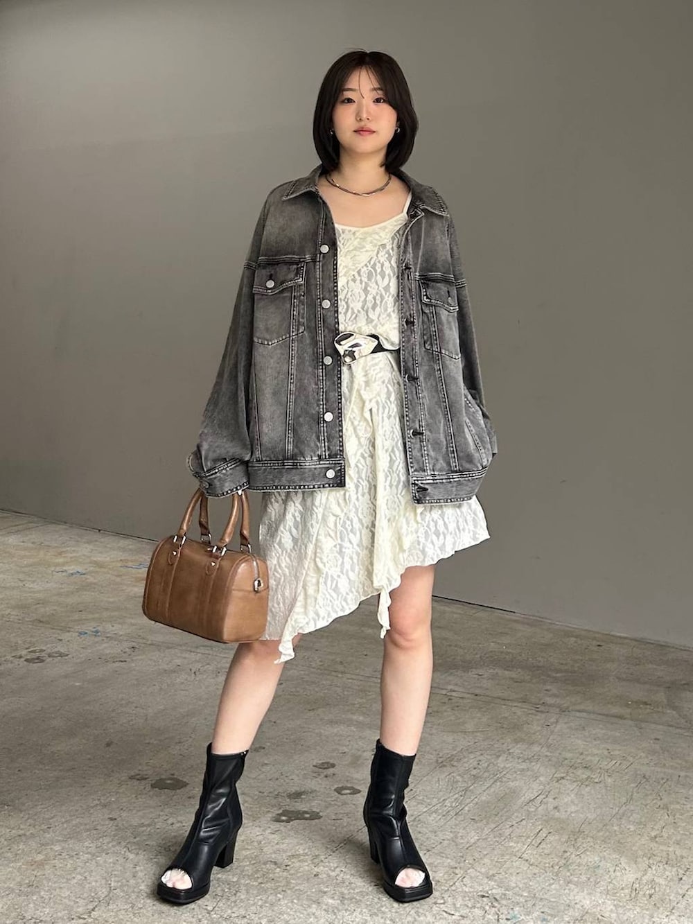 ブラウン系のボストンバッグ、ブラック系のブルゾン、ホワイト系のチュニックを着用したレディースの春コーディネートの4枚目の写真