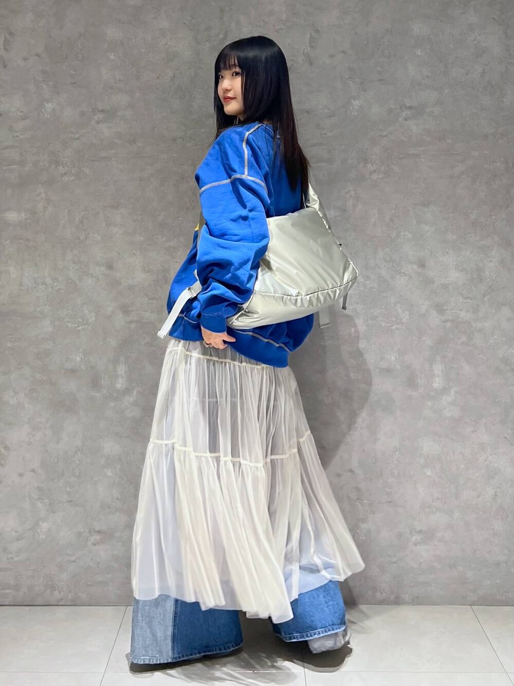 シルバー系のショルダーバッグ、ホワイト系のスカート、ブルー系のデニムパンツを着用したレディースの春コーディネートの3枚目の写真