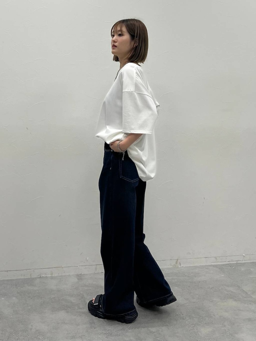 ブルー系のデニムパンツ、ブラック系のサンダル、ホワイト系のTシャツ/カットソーを着用したレディースの夏コーディネートの2枚目の写真