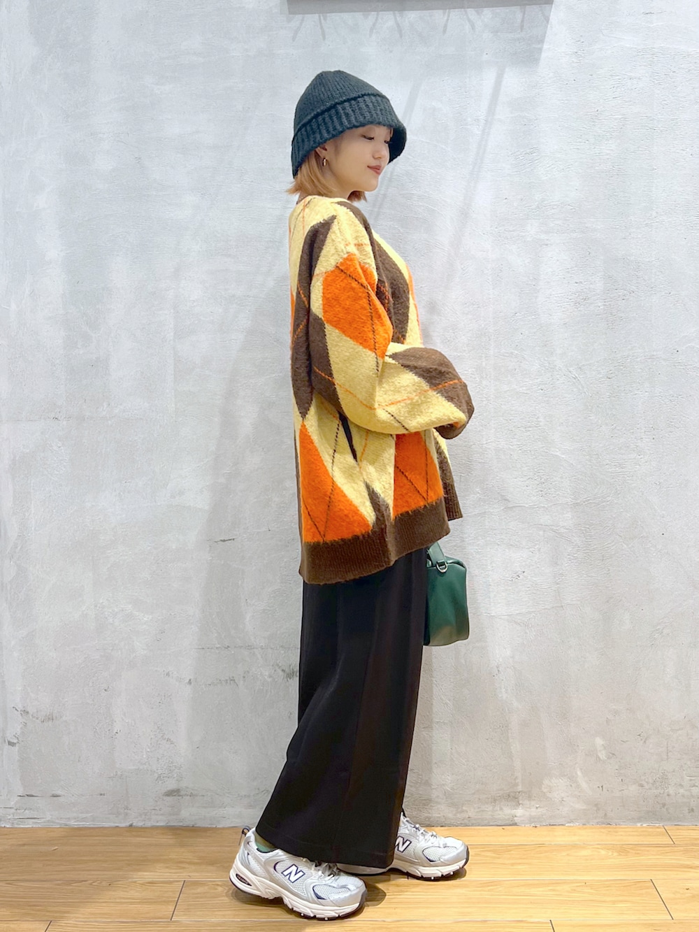 グリーン系のショルダーバッグ、ブラウン系のカーディガン/ボレロ、ブラック系のスカートを着用したレディースの秋コーディネートの2枚目の写真