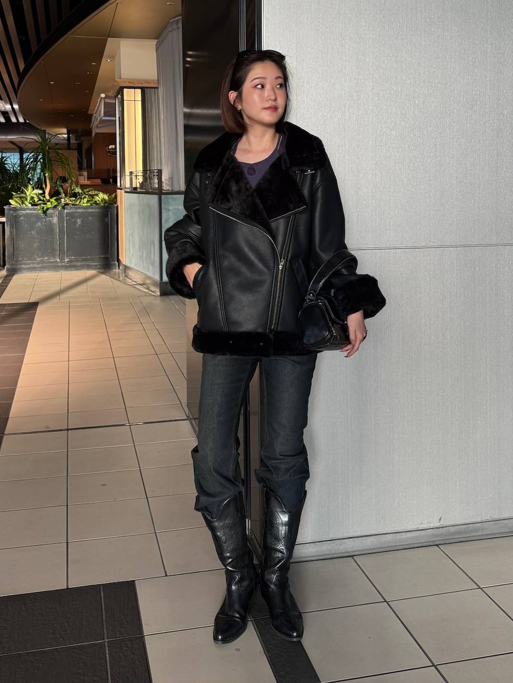 ブラック系のデニムパンツ、ブラック系のライダースジャケット、ブラック系のショルダーバッグを着用したレディースの秋コーディネートの3枚目の写真