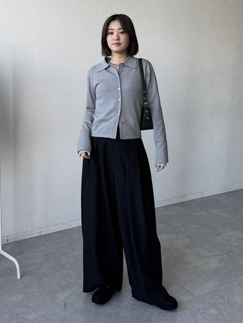 ブラック系のハンドバッグ、ブラック系のスラックス、ブラック系のモカシン/デッキシューズを着用したレディースの冬コーディネートの4枚目の写真