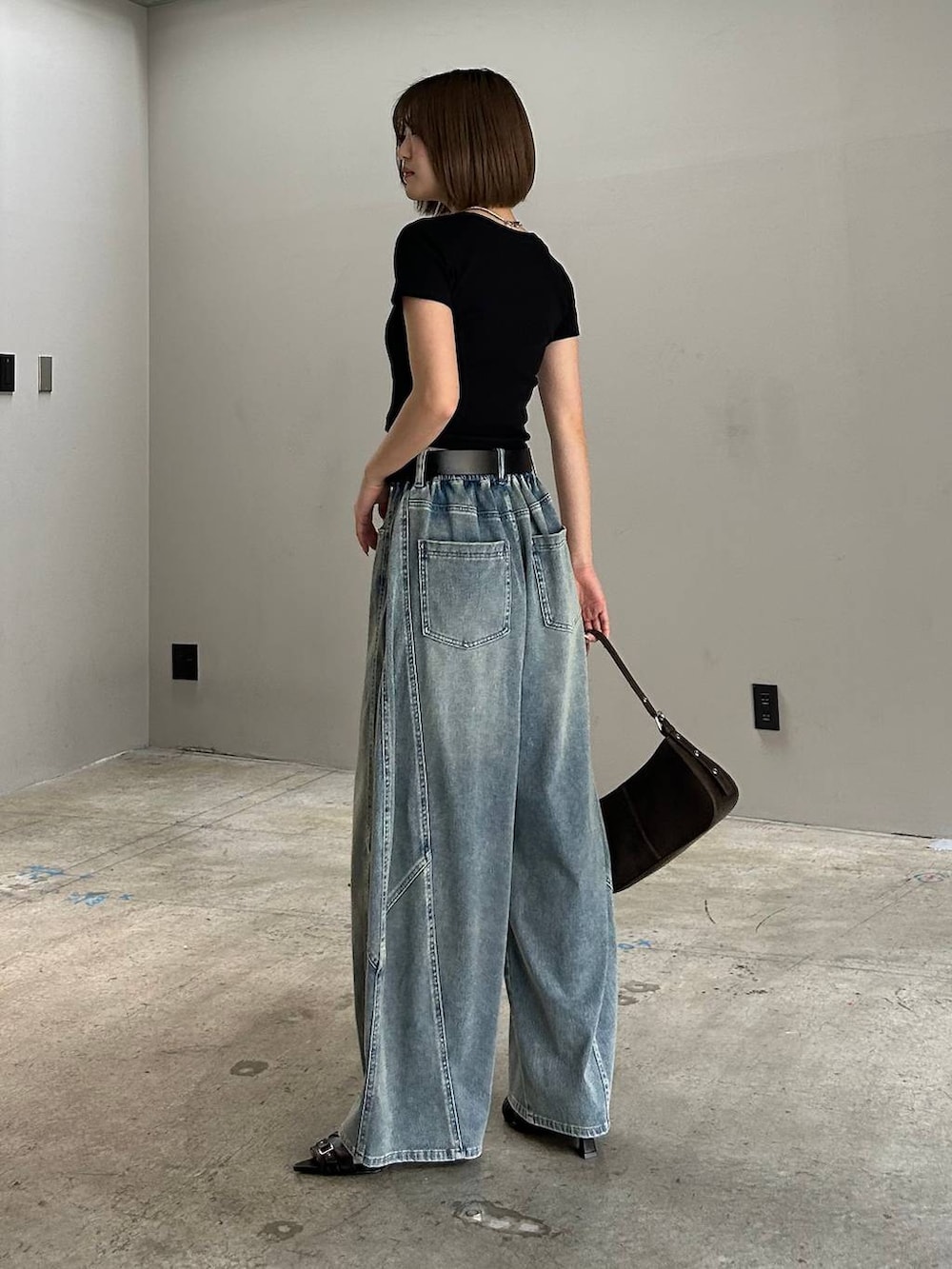 ブラック系のハンドバッグ、ブルー系のデニムパンツ、ブラック系のTシャツ/カットソーを着用したレディースの春コーディネートの6枚目の写真