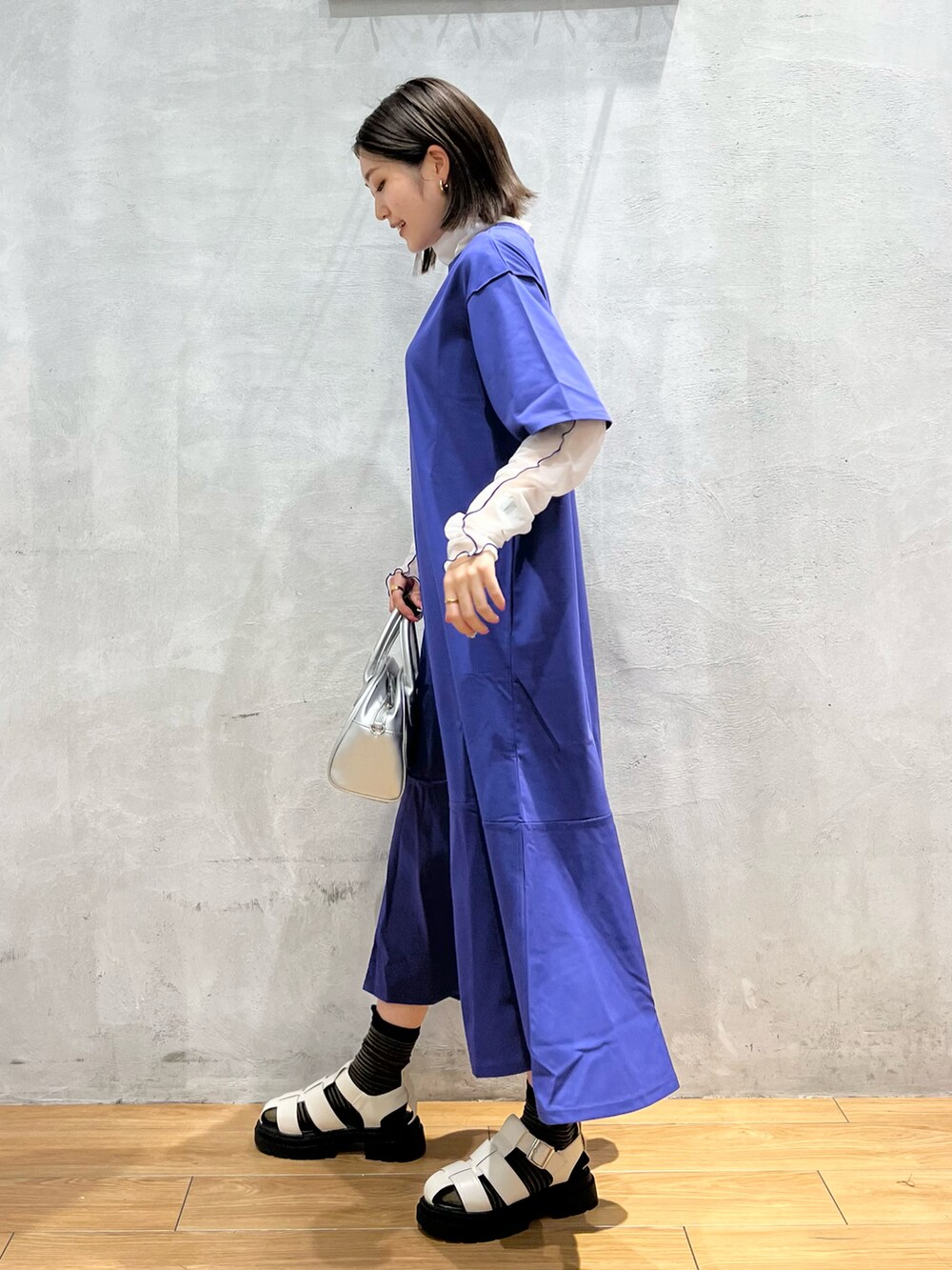 ブルー系のワンピース、ホワイト系のサンダル、シルバー系のショルダーバッグを着用したレディースの夏コーディネートの2枚目の写真