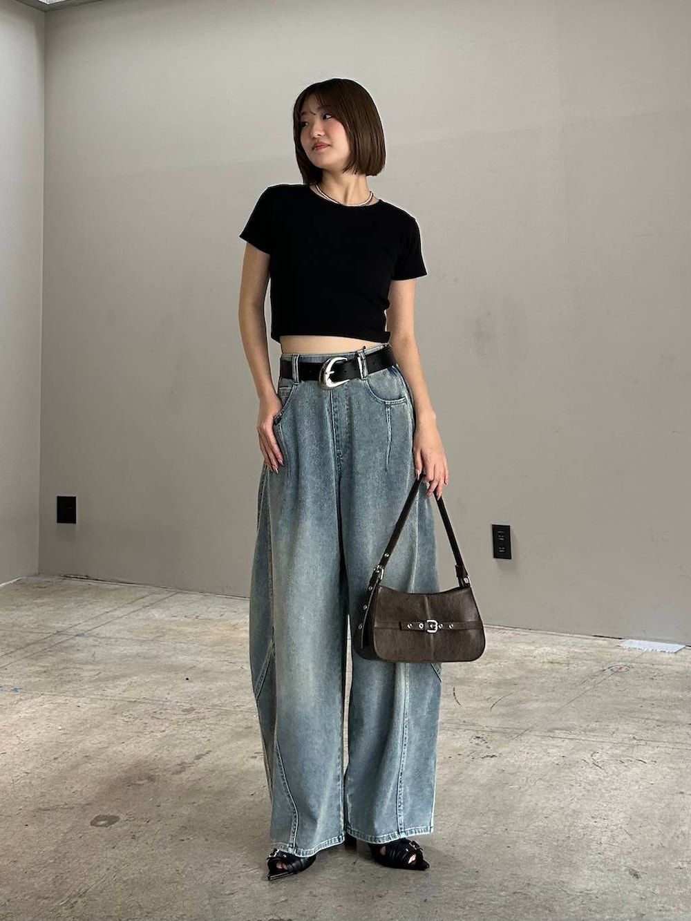 ブラック系のハンドバッグ、ブルー系のデニムパンツ、ブラック系のTシャツ/カットソーを着用したレディースの春コーディネートの5枚目の写真