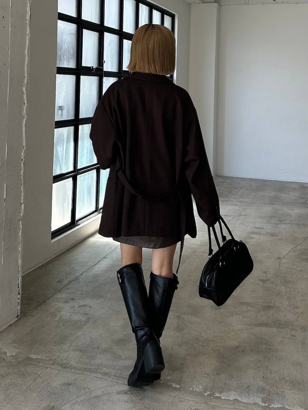 ブラック系のブーツ、ブラック系のボストンバッグ、ホワイト系のシャツ/ブラウスを着用したレディースの秋コーディネートの4枚目の写真