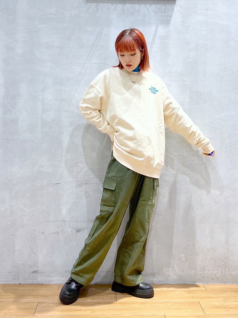 グリーン系のカーゴパンツ、ホワイト系のスウェット、ブラック系のブーツを着用したレディースの冬コーディネートの2枚目の写真