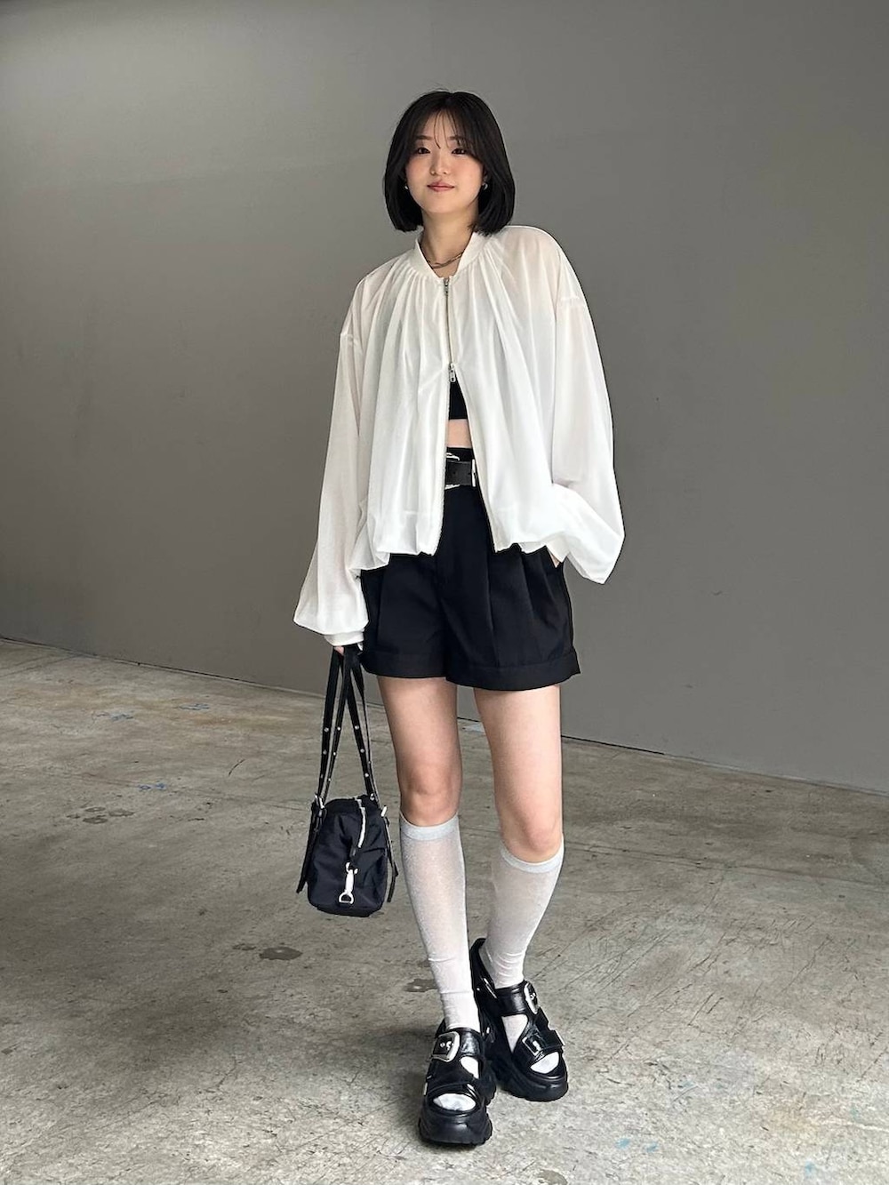 ブラック系のキャミソール、ホワイト系のブルゾン、ブラック系のサンダルを着用したレディースの春コーディネートの4枚目の写真