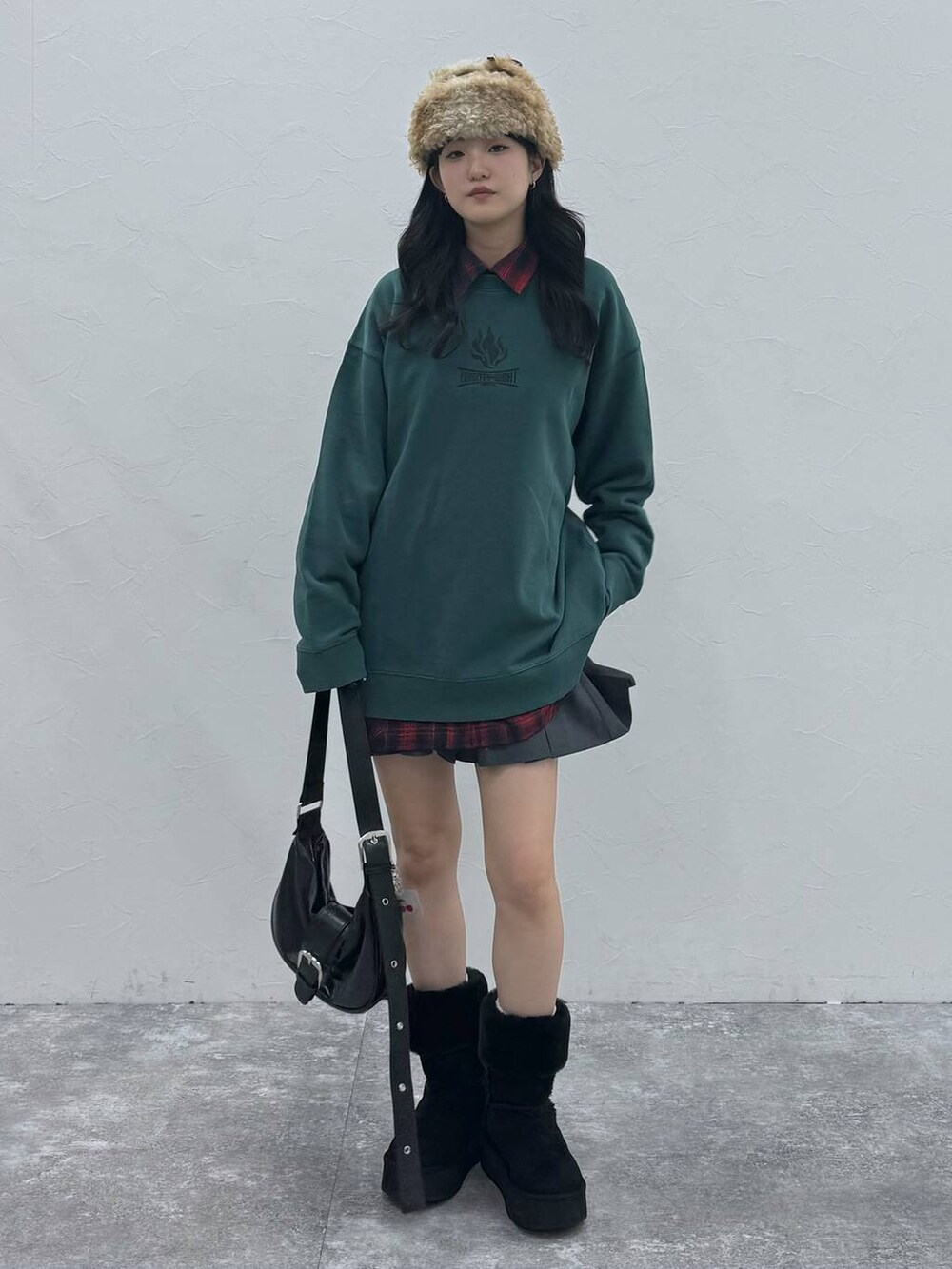 ブラック系のショルダーバッグ、ブラック系のブーツ、グリーン系のスウェットを着用したレディースの冬コーディネートの4枚目の写真