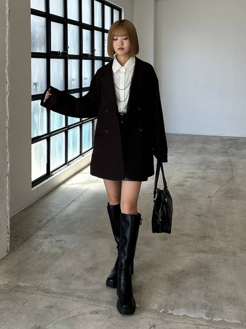 ブラック系のブーツ、ブラック系のボストンバッグ、ホワイト系のシャツ/ブラウスを着用したレディースの秋コーディネートの5枚目の写真