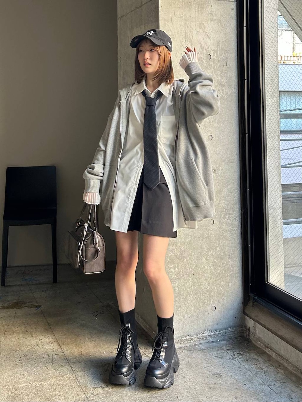 ブラック系のブーツ、ブラック系のスカート、グレー系のネクタイを着用したレディースの春コーディネートの3枚目の写真