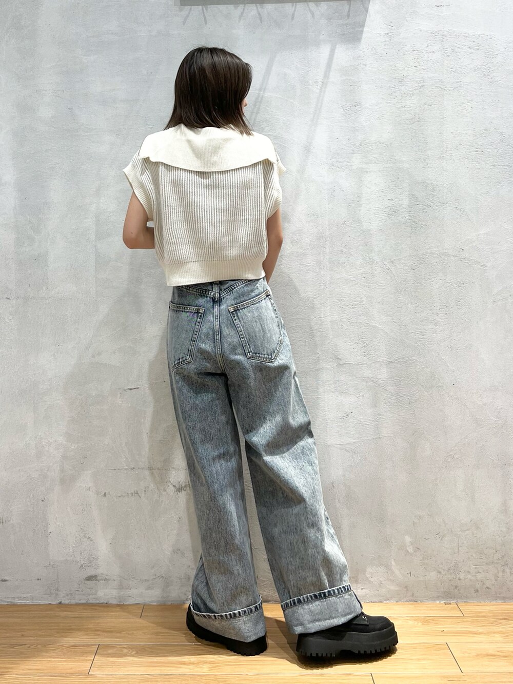 ホワイト系のニット/セーター、ブルー系のデニムパンツ、ブラック系のブーツを着用したレディースの夏コーディネートの4枚目の写真