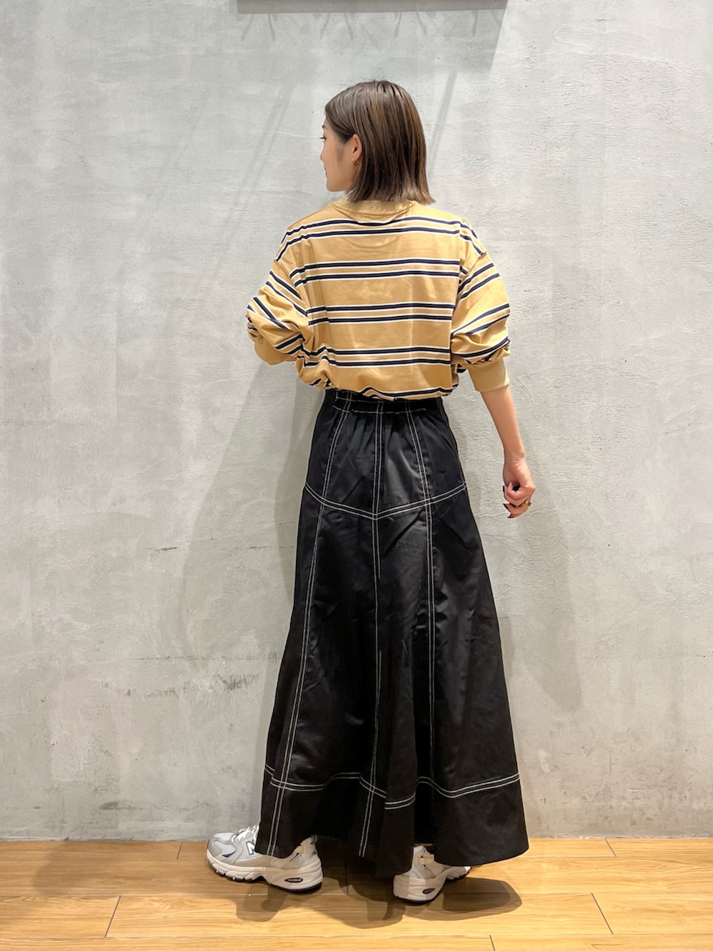 ブラック系のスカート、ベージュ系のTシャツ/カットソーを着用したレディースの秋コーディネートの3枚目の写真