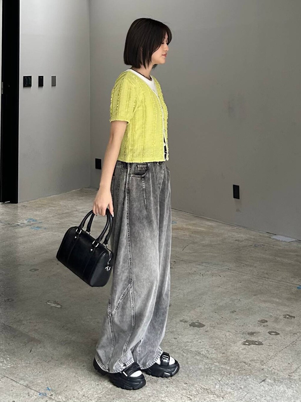 ホワイト系のボストンバッグ、ブラック系のデニムパンツ、ブラック系のサンダルを着用したレディースの春コーディネートの2枚目の写真