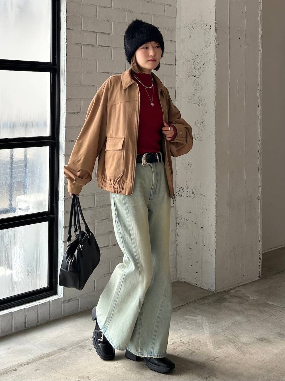 ブルー系のデニムパンツ、ブラック系のボストンバッグ、イエロー系のブルゾンを着用したレディースの秋コーディネートの3枚目の写真