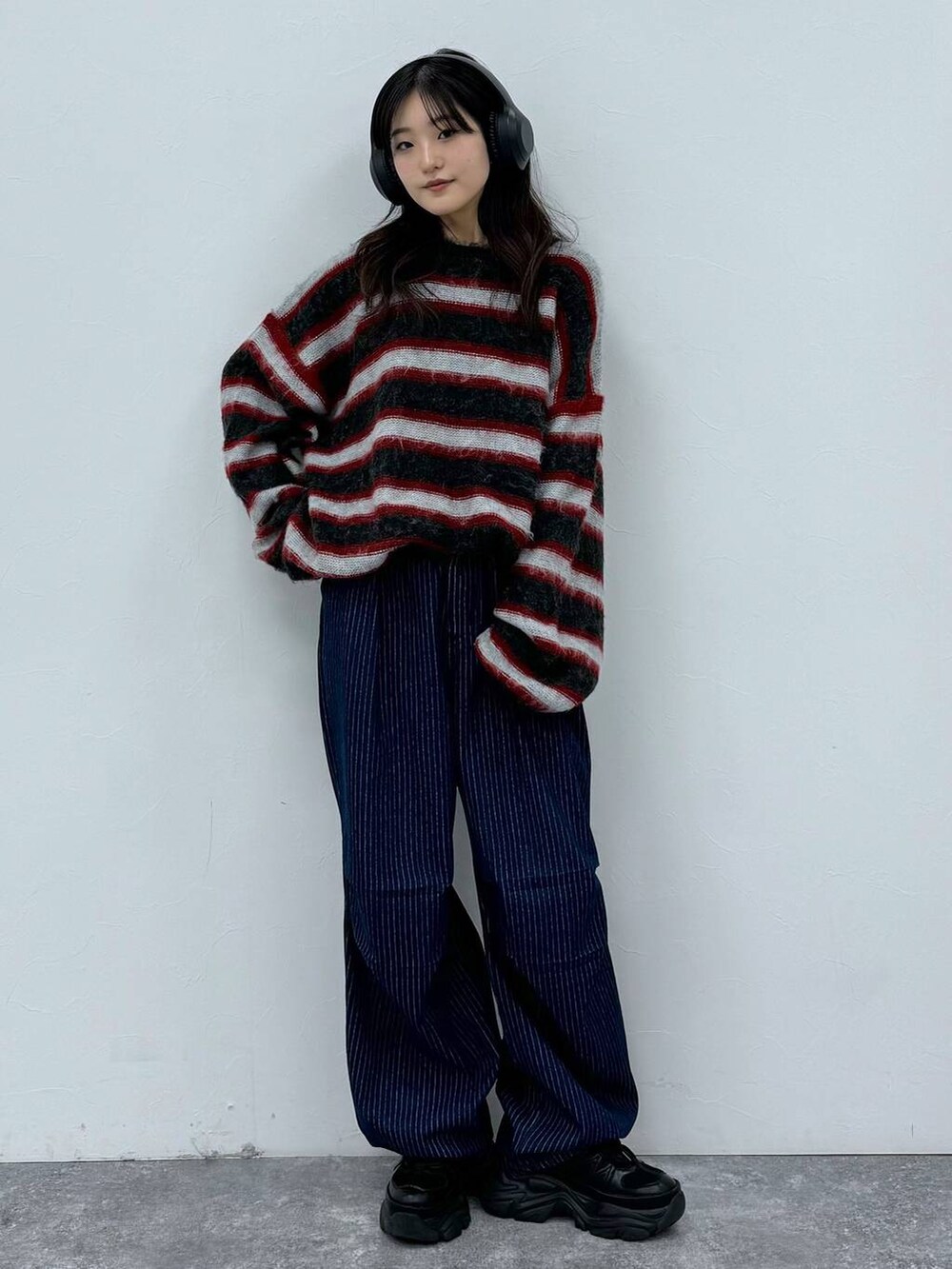 ブラック系のスニーカー、ブルー系のデニムパンツ、レッド系のニット/セーターを着用したレディースの秋コーディネートの4枚目の写真