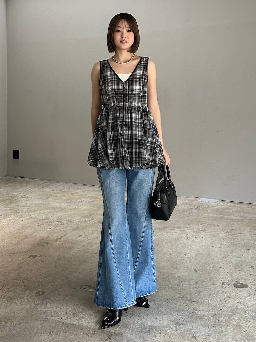 ブルー系のデニムパンツ、ブラック系のボストンバッグ、ブラック系のサンダルを着用したレディースの春コーディネートの2枚目の写真