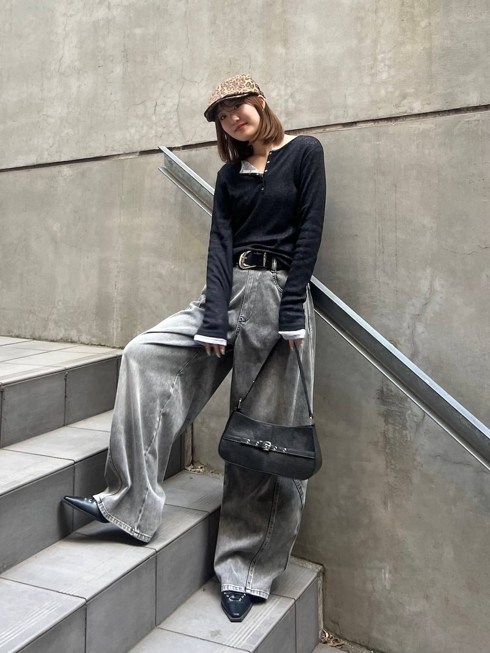 ブラック系のハンドバッグ、ブラック系のデニムパンツ、ブラック系のベルトを着用したレディースの冬コーディネートの3枚目の写真