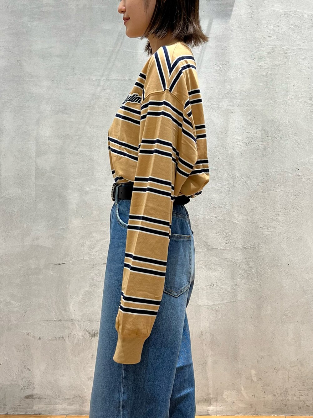 ブルー系のデニムパンツ、ブラック系のショルダーバッグ、グレー系のスニーカーを着用したレディースの秋コーディネートの4枚目の写真