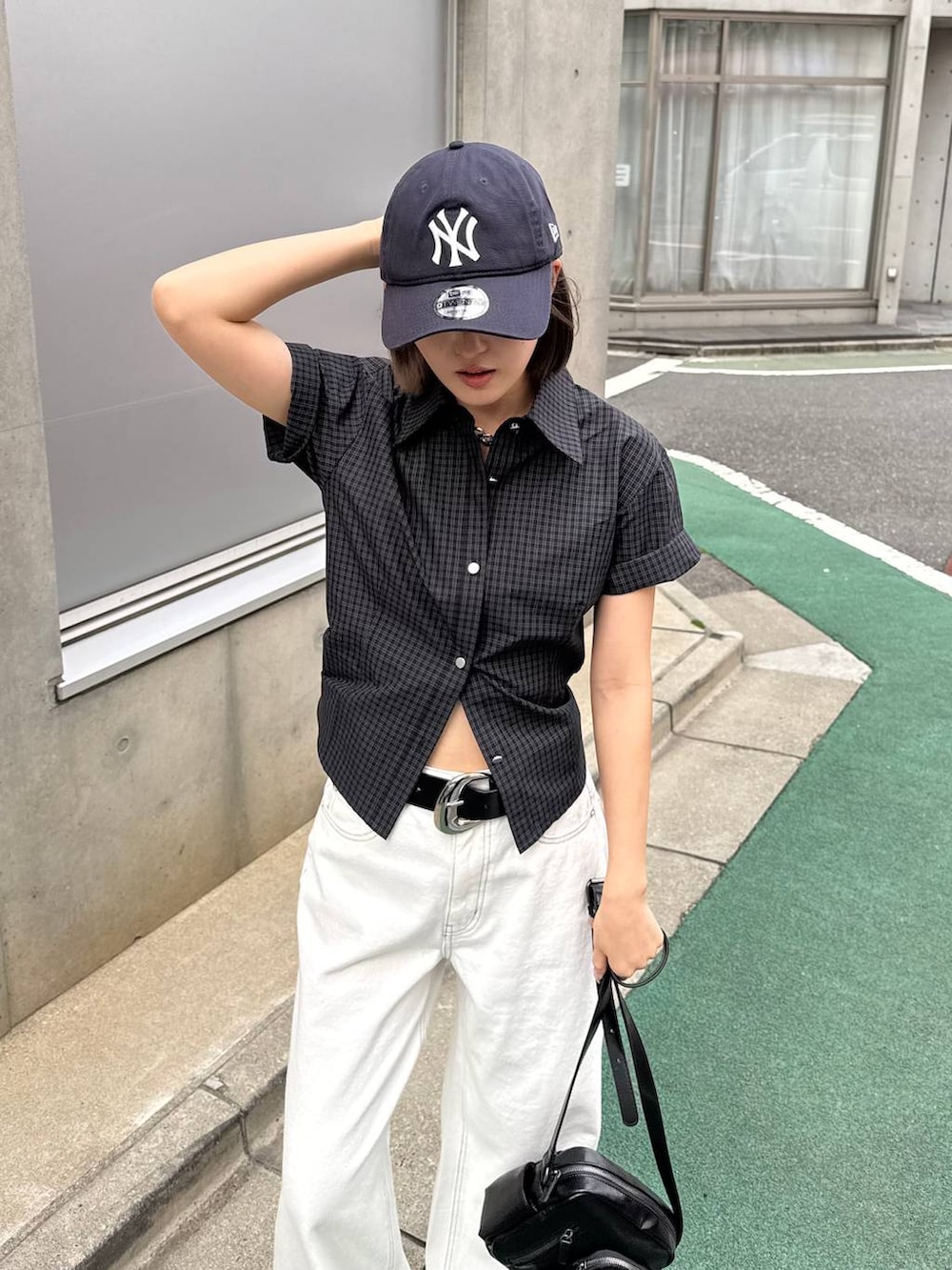 ホワイト系のデニムパンツ、ブラック系のショルダーバッグ、ブラック系のサンダルを着用したレディースの春コーディネートの4枚目の写真