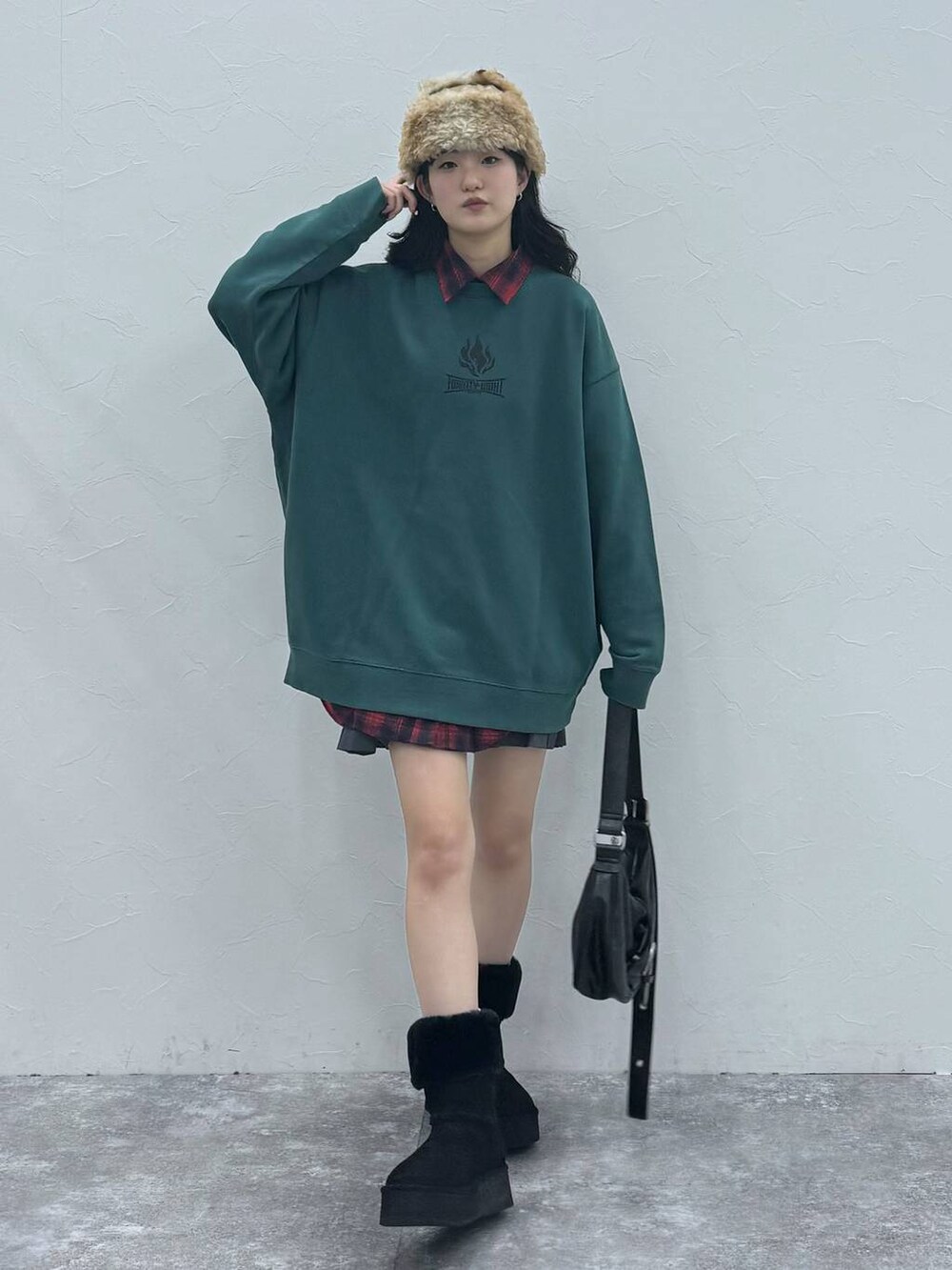 ブラック系のショルダーバッグ、ブラック系のブーツ、グリーン系のスウェットを着用したレディースの冬コーディネートの2枚目の写真