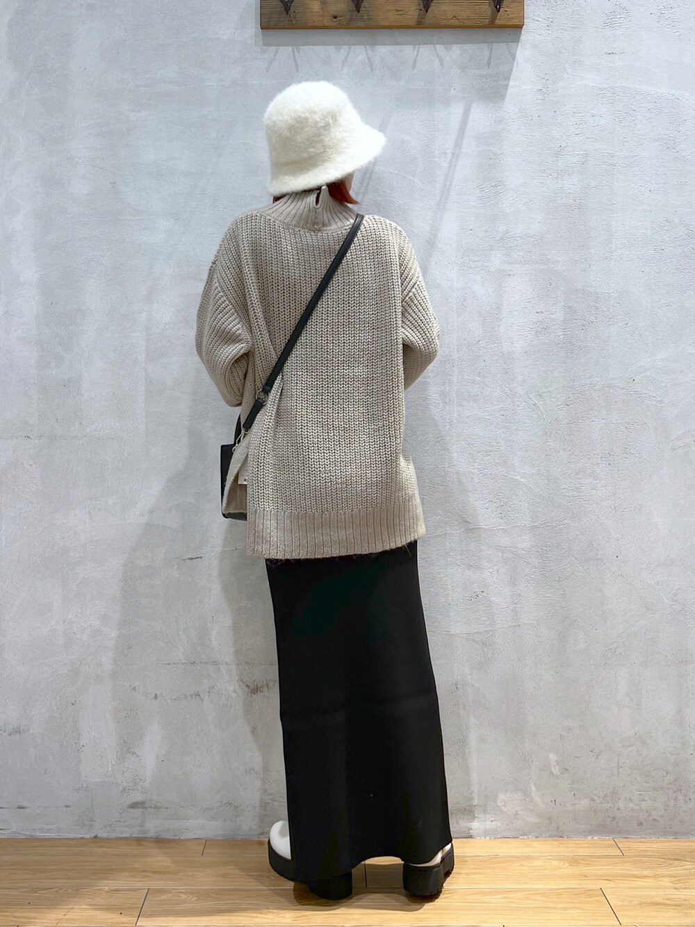 ブラック系のショルダーバッグ、ベージュ系のニット/セーター、ブラック系のスカートを着用したレディースの秋コーディネートの3枚目の写真