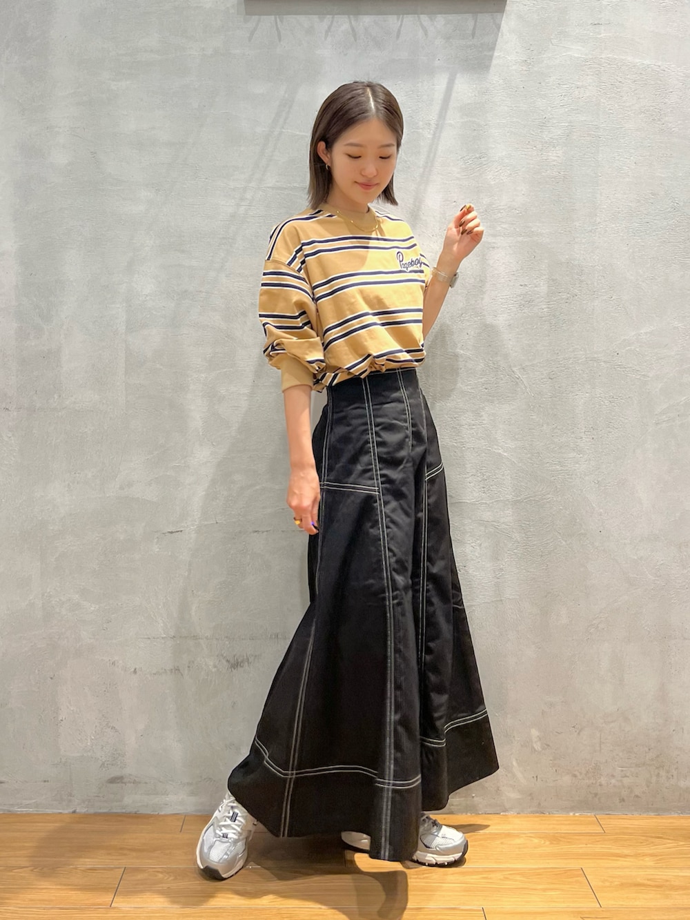 ブラック系のスカート、ベージュ系のTシャツ/カットソーを着用したレディースの秋コーディネートの4枚目の写真