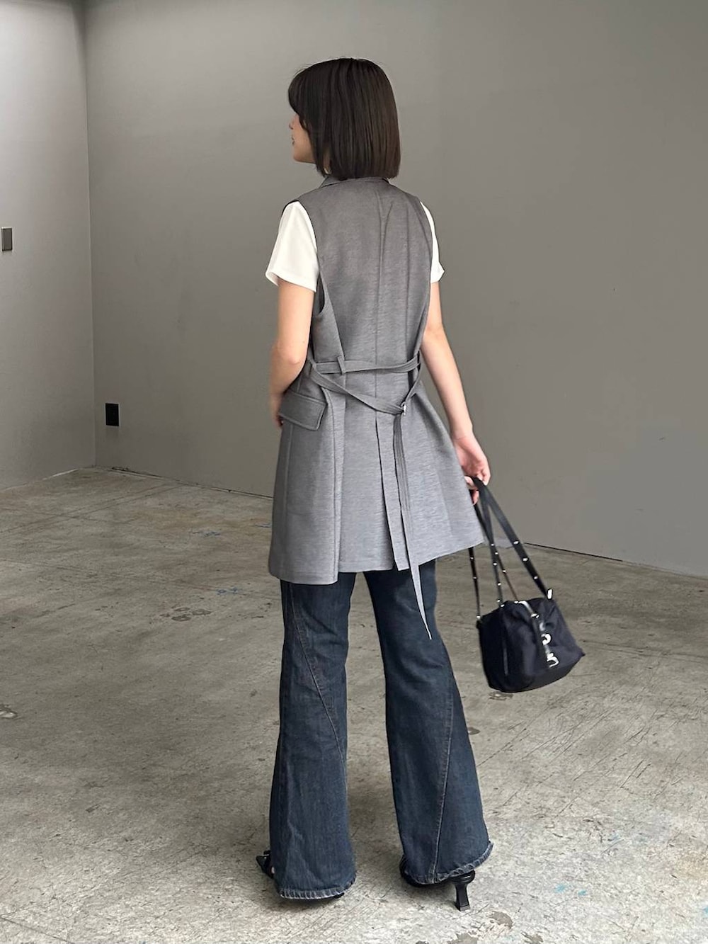 ブルー系のデニムパンツ、ブラック系のサンダル、グレー系のテーラードジャケットを着用したレディースの春コーディネートの3枚目の写真