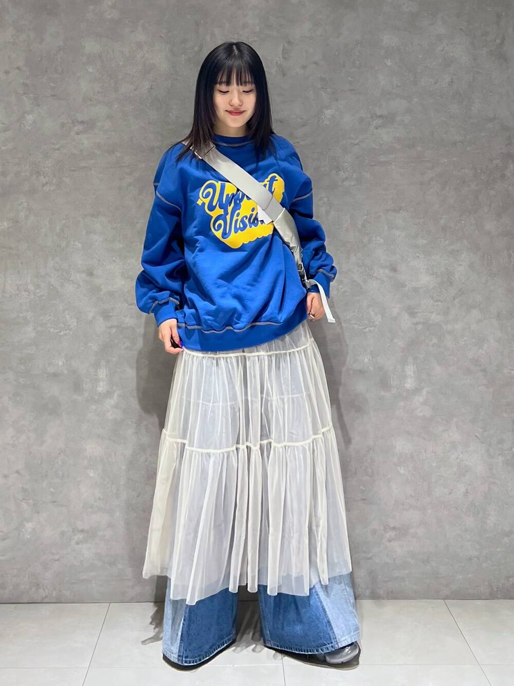 シルバー系のショルダーバッグ、ホワイト系のスカート、ブルー系のデニムパンツを着用したレディースの春コーディネートの6枚目の写真