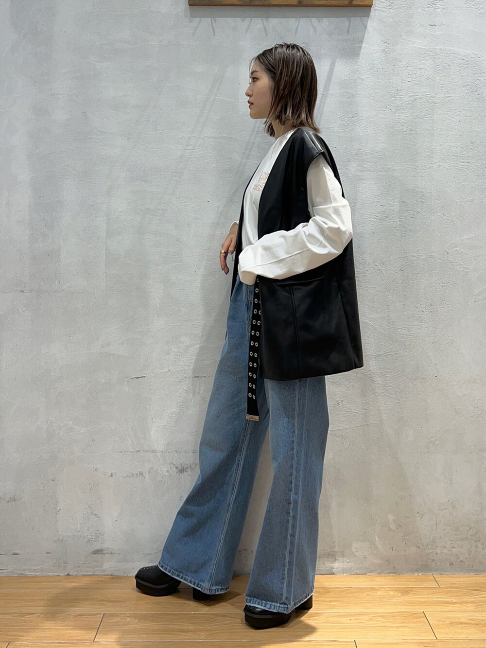 ブルー系のデニムパンツ、ブラック系のブーツ、ブラック系のその他アウターを着用したレディースの秋コーディネートの2枚目の写真