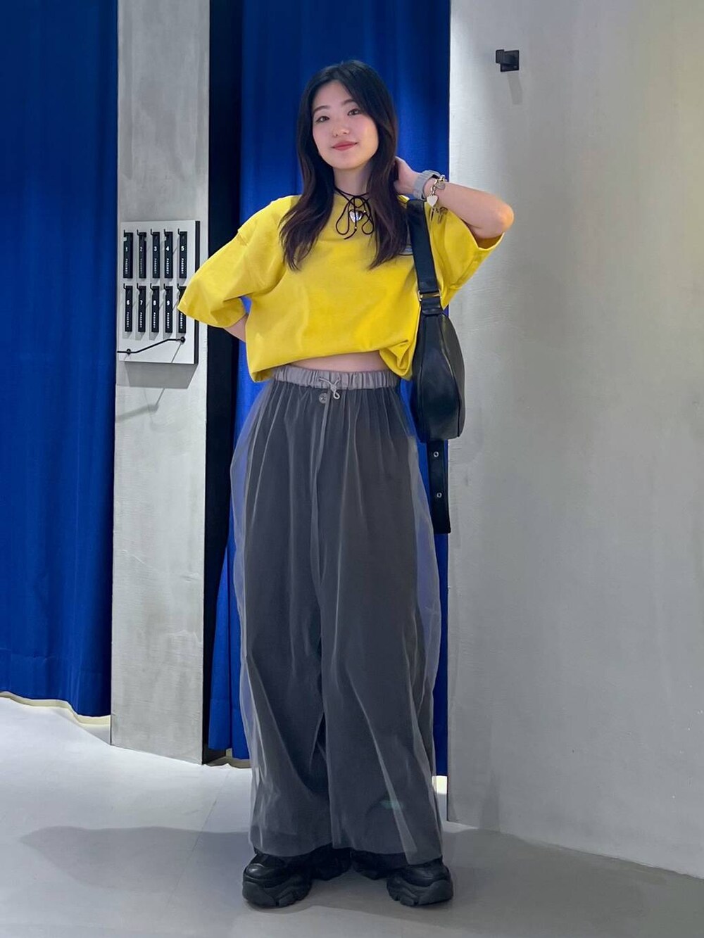 ブラック系のスニーカー、ブラック系のショルダーバッグ、イエロー系のTシャツ/カットソーを着用したレディースの夏コーディネートの2枚目の写真