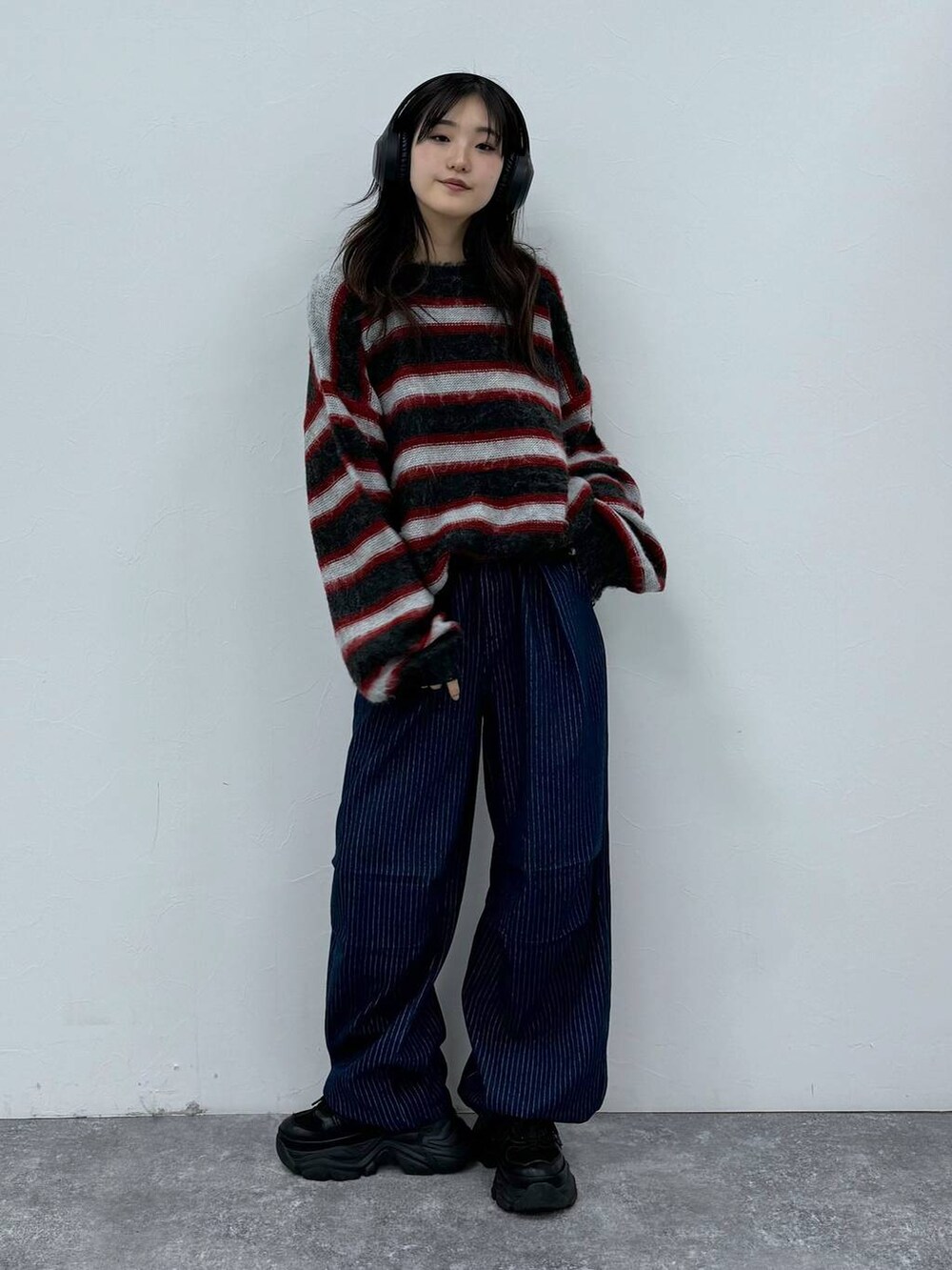 ブラック系のスニーカー、ブルー系のデニムパンツ、レッド系のニット/セーターを着用したレディースの秋コーディネートの3枚目の写真