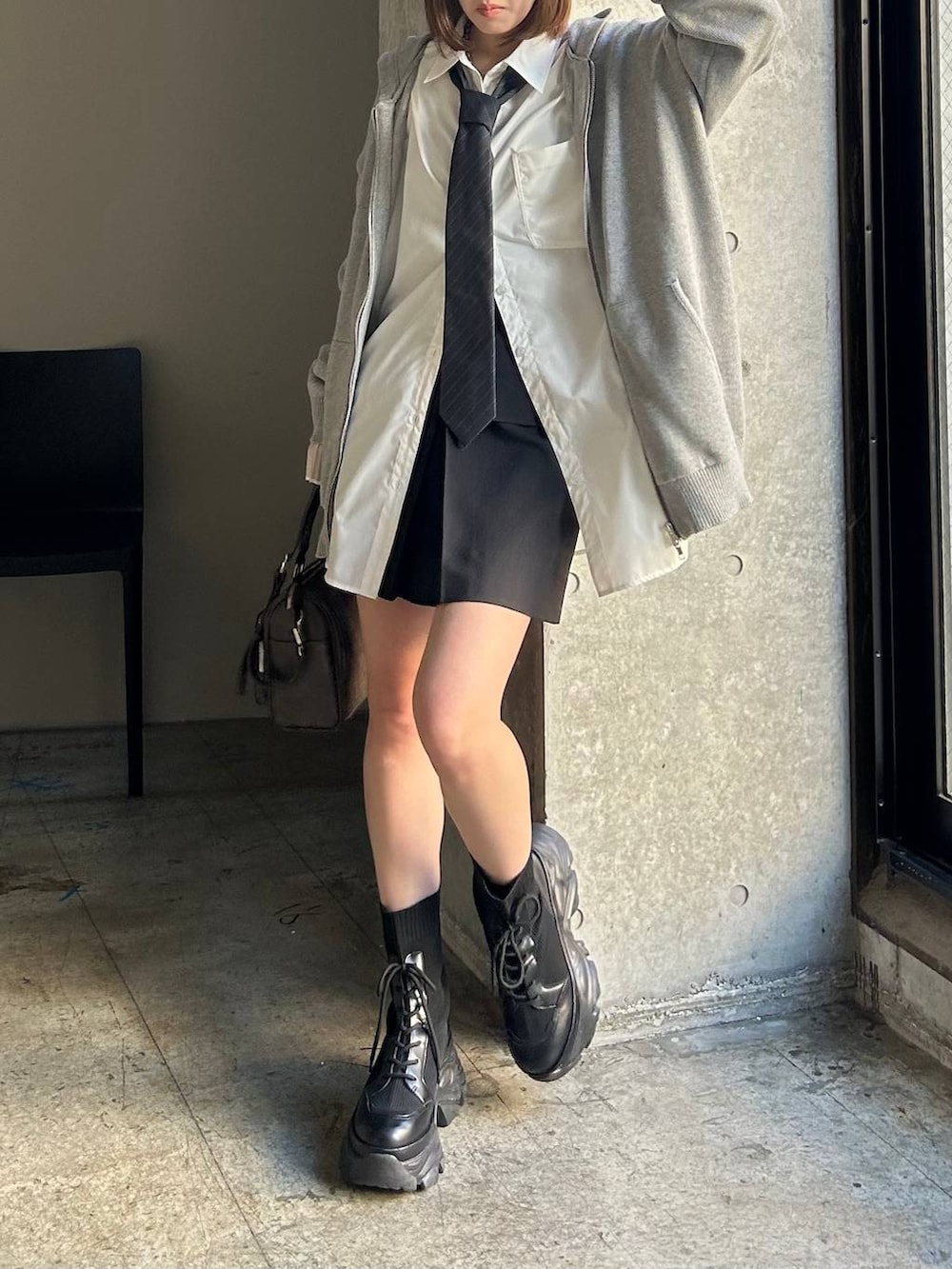 ブラック系のブーツ、ブラック系のスカート、グレー系のネクタイを着用したレディースの春コーディネートの4枚目の写真