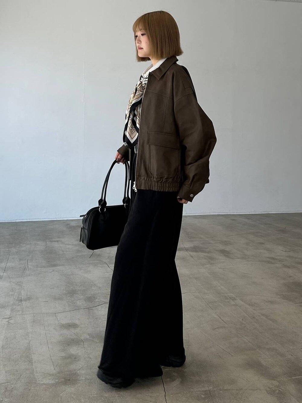 ブラック系のブーツ、ブラック系のスウェットパンツ、ブラック系のボストンバッグを着用したレディースの秋コーディネートの3枚目の写真