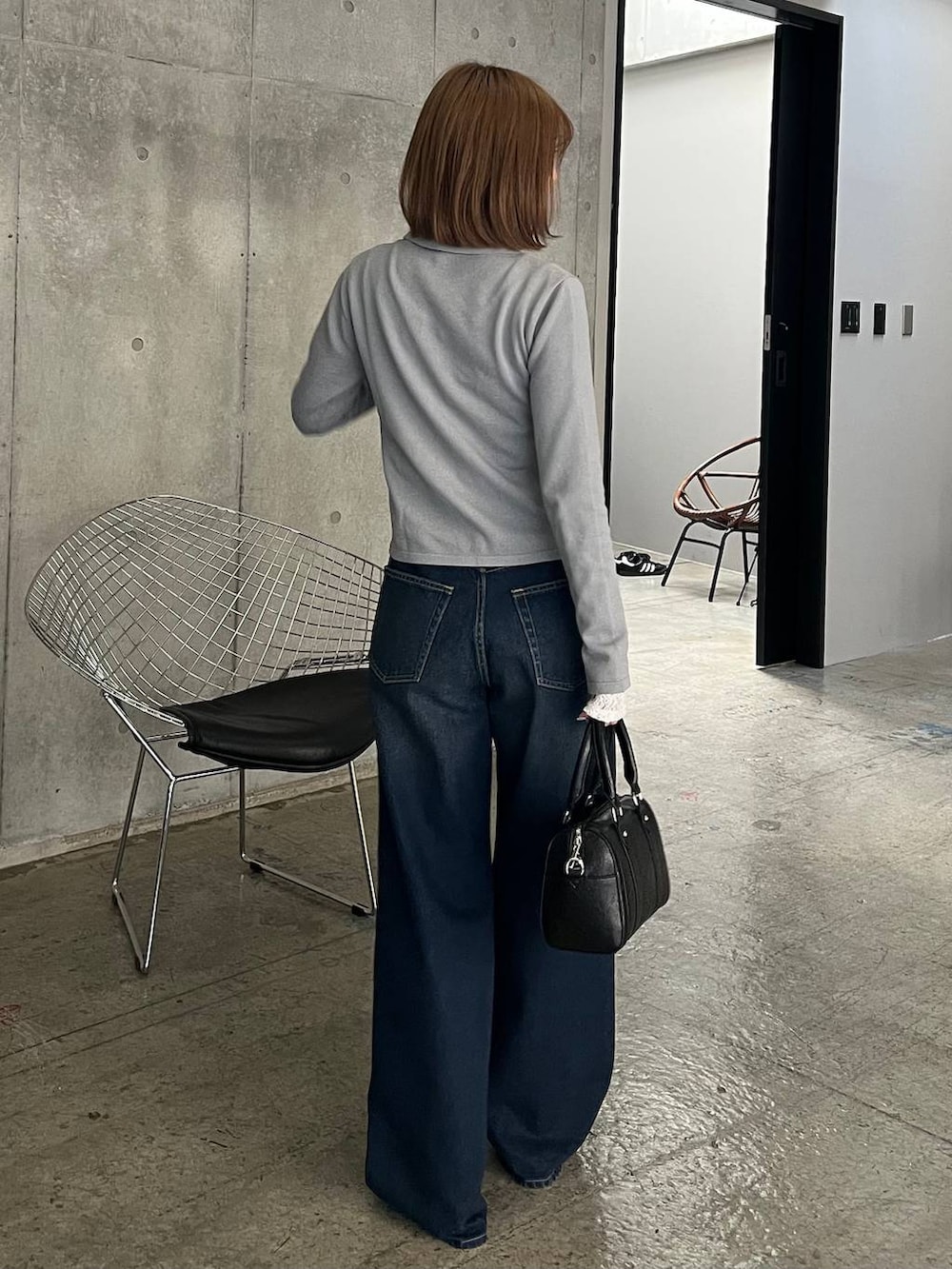 ブルー系のスラックス、ブラック系のボストンバッグ、ブラック系のサンダルを着用したレディースの冬コーディネートの3枚目の写真