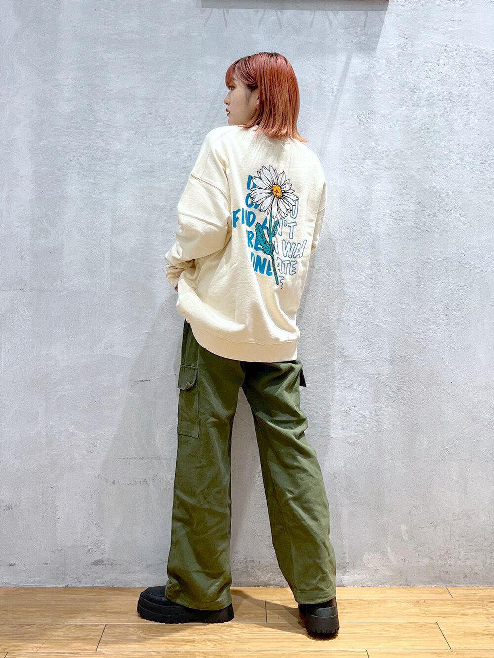 グリーン系のカーゴパンツ、ホワイト系のスウェット、ブラック系のブーツを着用したレディースの冬コーディネートの3枚目の写真