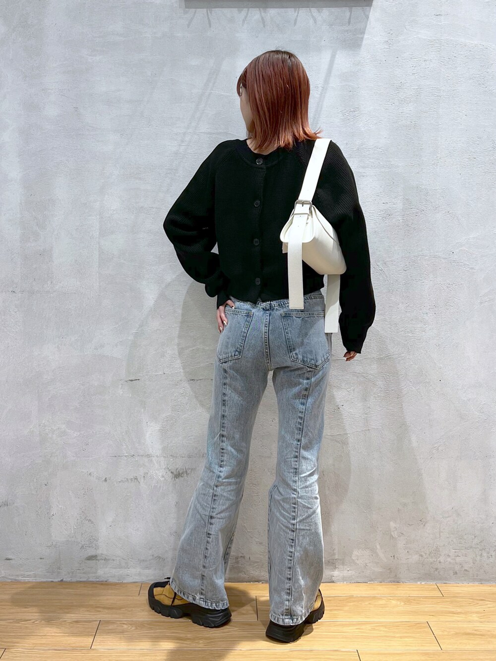 ブルー系のデニムパンツ、ブラック系のカーディガン/ボレロ、ホワイト系のトートバッグを着用したレディースの冬コーディネートの2枚目の写真